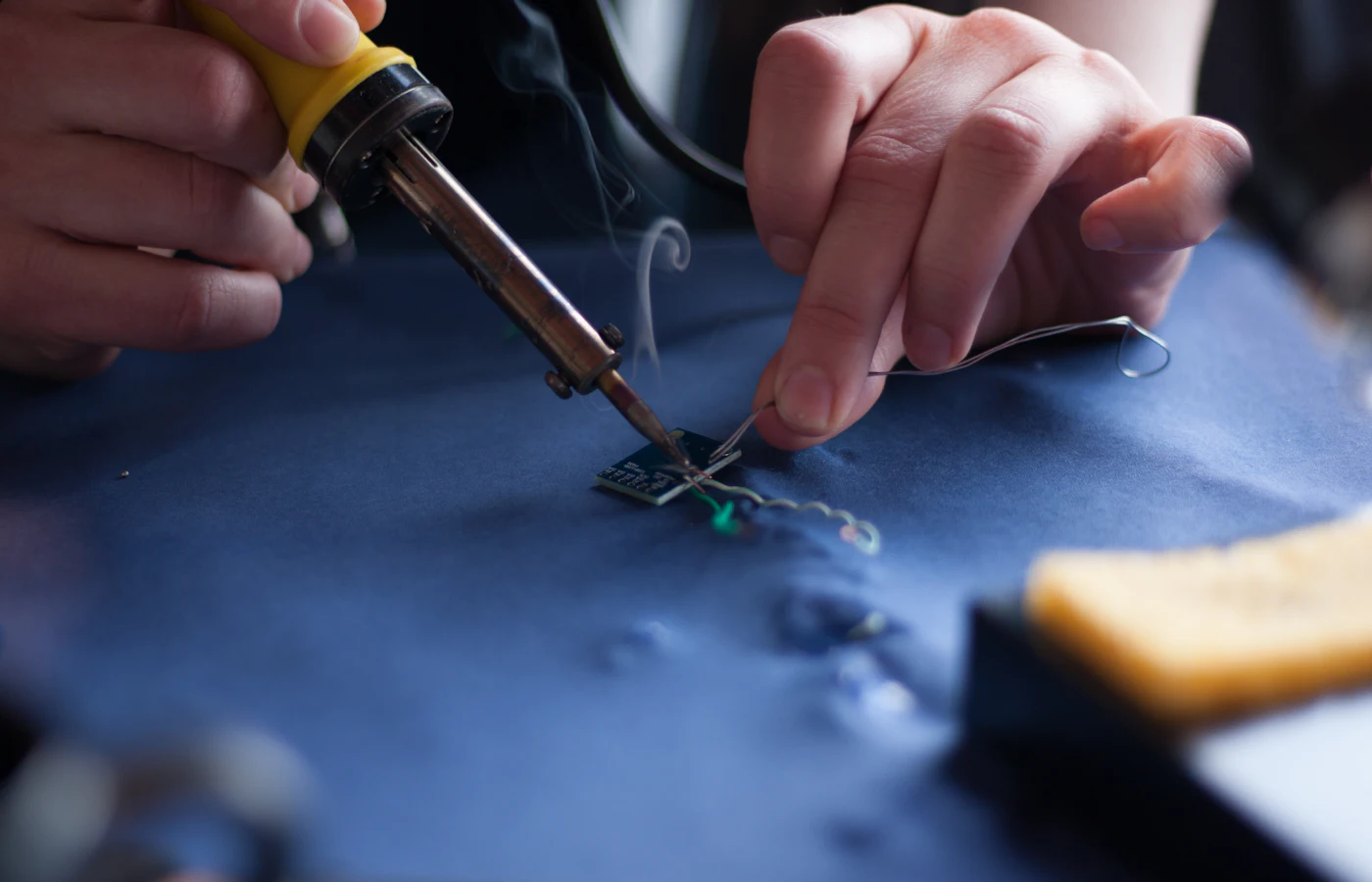 Close-up of hands soldering a small circuit board